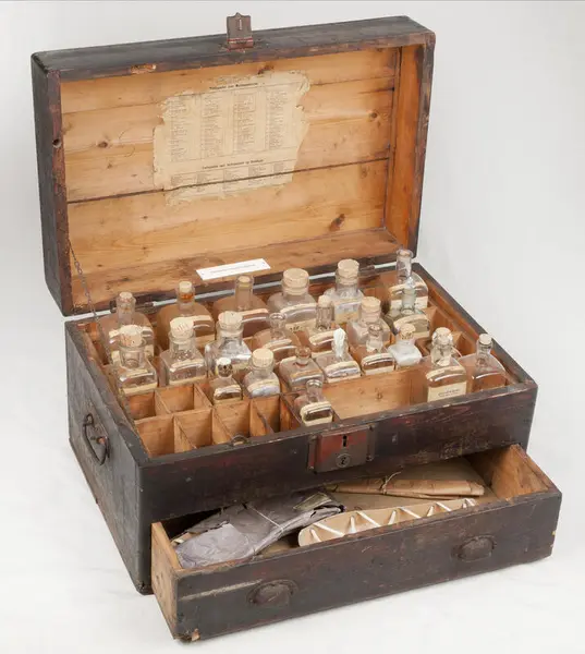 Bildet viser en kiste med åpent lokk og åpen skuff. Det er fylt med mange små flasker