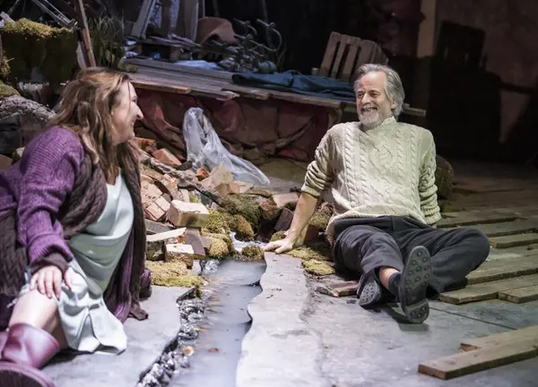 Teaterscene: En mann og en kvinne sitter på bakken og smiler til hverandre. 