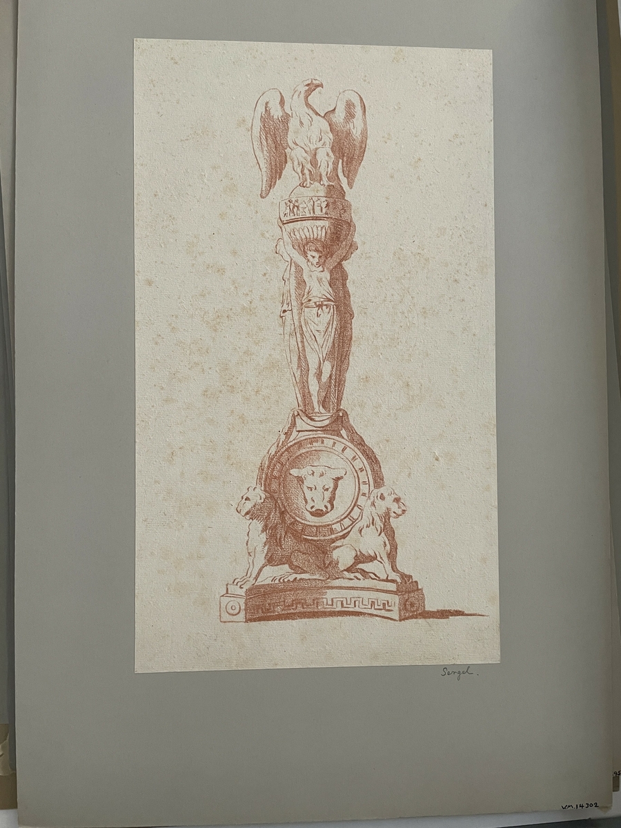 "Monument, överst en örn på ett klot, som uppbäres av tre ynglingar med ryggarna mot varandra. Nederst på en låg konsoll sitter tvenne lejon, vilka uppbär det hela på sina ryggar, mellan lejonen och ynglingarna en cirkelrund formdel med ett stort lejonhuvud i mitten.".