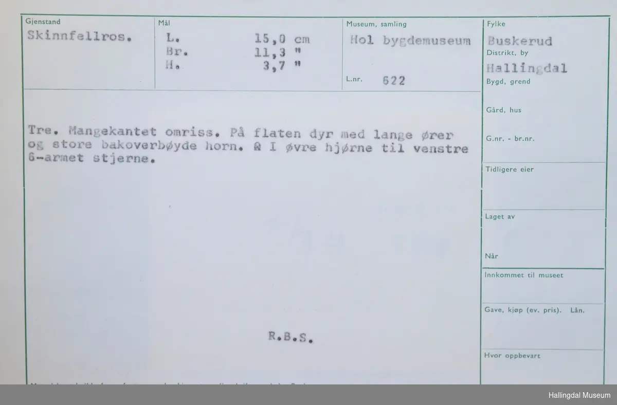 Skinnfellros. Tre. Mangekantet omriss. På flaten dyr med lange ører og store bakoverbøyde horn. I øvre hjørne til venstre 6-armet stjerne.
L:15 cm, Br: 11,3 cm, H: 3,7 cm
R.B.S.