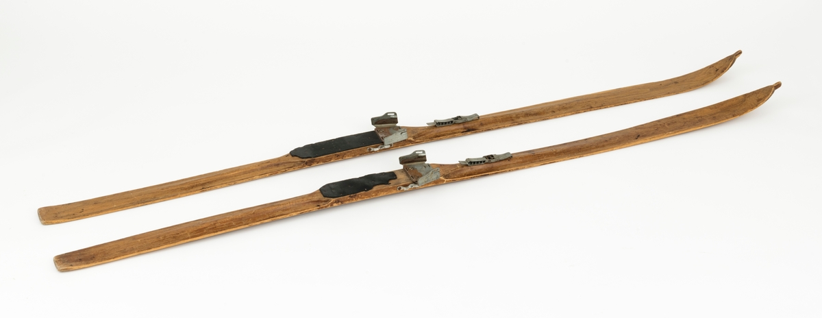 PATENT NO 1, det står også speisfisert hva som er høyre og venstre ski med L - R. Ligner på en KANDAHAR BINDING, mangler wiren til hælfeste. Skiene har en svak kromning foran og bak fotsteget. Tuppen har en svak bøy, tuppene har også det vi kaller "sukkerbittupp" Skiene er også litt oppbygd bak. 
