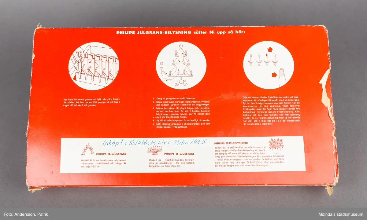 En papplåda som innehåller en elektrisk julgransbelysning av märket Philips. Lådans utsida har en målad vinterbild som föreställer ett vinterlandskap med tre tomtar ute i snön. I mitten på bilden finns en julgran med belysning. Till vänster på bilden, står två rådjur och tittar på tomtarna. 
På lådans baksida finns en monteringsanvisning. Nedtill finns en signatur som anger att det Erik Forsman som har målat bilden.
I lådan finns en elektrisk ljusslinga med 16 ljus. Det finns även en tiilhörande plastpåse med 15 glödlampor.
Julgransbelysningen är inköpt 1965 av Gerd och Jan Kilnäs som bodde i Kallebäck. Belysningen är inköpt på Kallebäcks Livs den 23 december 1965. Gerd och Jan Kilnäs flyttade till Mölnlycke år 1968 och har använt ljusslingan varje år fram till 2014, då togs den över av Maria Kilnäs.
Elektriska julgransbelysningar började tillverkas i slutet på 1800-talet. Det var först under mellankrigstiden som den började användas i större utsträckning.
Innan det använde man stearinljus.
