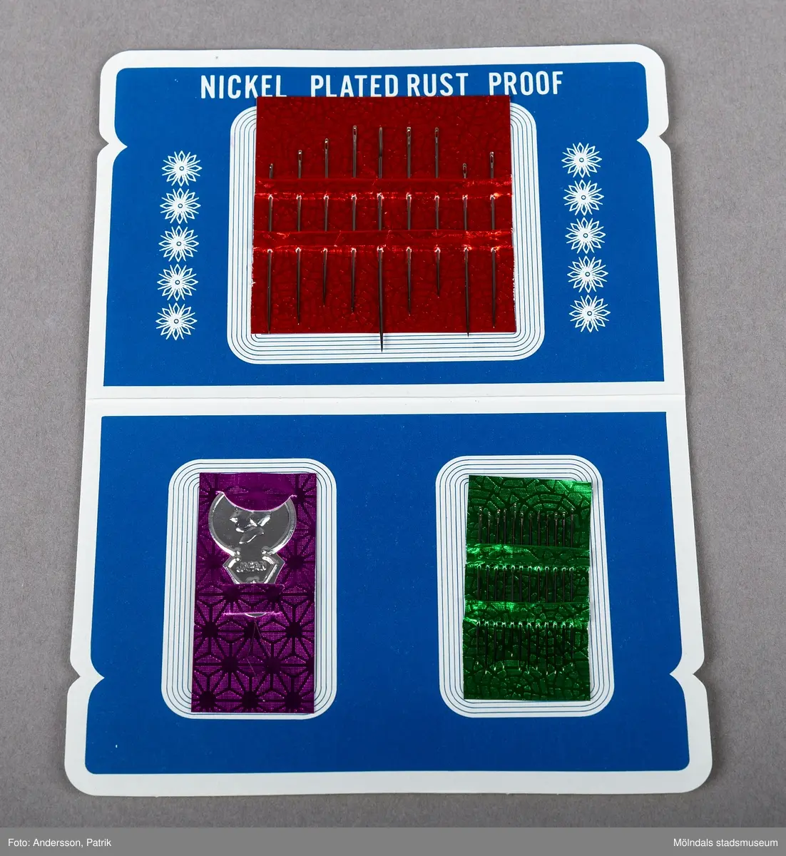 En förpackning med synålar från Japan. Förpackningen innehåller synålar. På framsidan finns en bild på fyra kvinnor som sitter och umgås och syr.