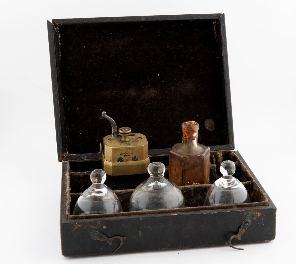 En liten kasse med krukker og en messingdings.