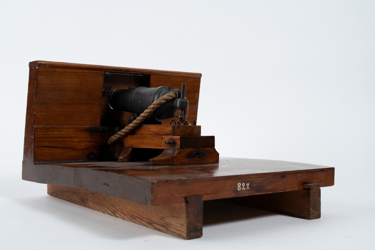 Kanonmodell: 24-pundig karronadlavett av engelsk modell, helt i trä, med karronad. Karronaden svartbetsad, lavetten fernissad. Lavetten L = 345 mm B = 310 mm H = 205 mm.