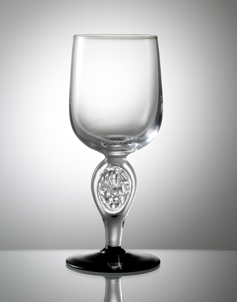 "Skål". Formgivare: Lars Hellsten. "Jag är stadig". Jubileumsglas till Orrefors 100-årsjubileum 1998. Beskrivande text till glaset: "Jag är stadig".

Tulpanformad, slät kupa. Ben med fågelmotiv i relief samt svart fot.