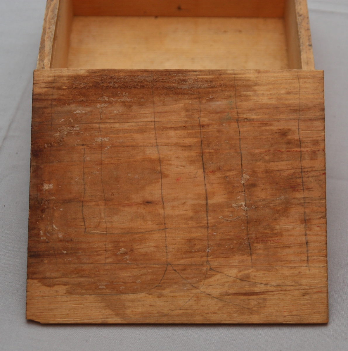 Bygglåda, rektangulär låda av furu med inskjutbart lock från Gemla Leksaksfabriks Aktiebolag (1866-1884). Utan leksaker innuti. Etikett på locket som föreställer en logga med en gunghäst omgiven av tre vita blommor. Etikettens yttre kanter har ett dekorelement föreställande ett slingrande band.