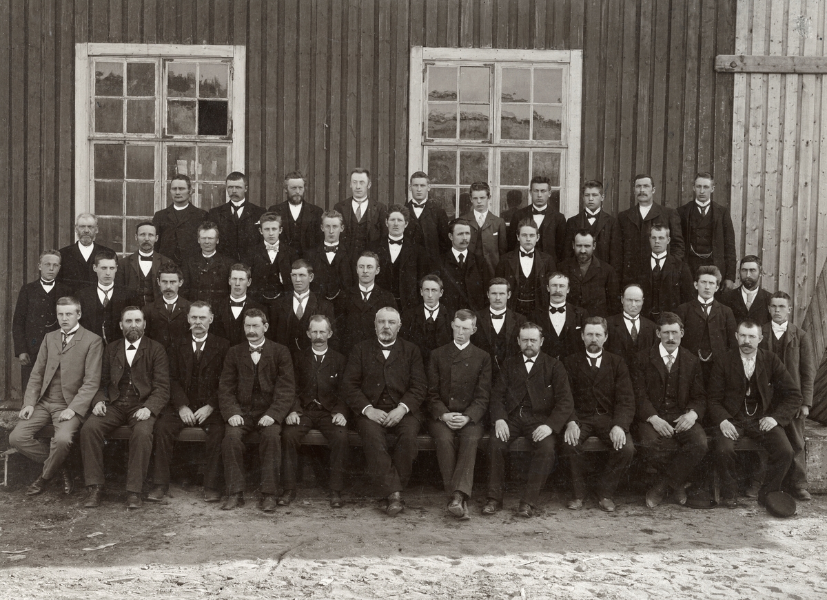 Gruppebilde av arbeidsstokken ved Klevfos Cellulose & Papirfabrik i Løten i Hedmark. Ifølge tradisjonen skal fotografiet være tatt 1905, i forbindelse med festligheter som var utløst av oppløsninga av unionen med Sverige. Fotografiet er i hvert fall tatt mens Otto Andersén var fabrikkbestyrer. Han sitter sentralt (nr. 6 fra venstre) i første rekke. Medarbeidere er oppstilt på fire rekker, antakelig med krakker som løfter karene på de to bakerste rekkene opp, slik at alle er synlige, i hvert fall fra brystpartiet og oppover. Mye tyder på at de fleste av de kontoransatte hadde fått sitteplass i første rekke. Fabrikkbestyrer Otto Andersén var imidlertid ikke med. Alle de 44 mennene er dresskledde og de flestre har kvite skjortesnipper og slips. Gruppa er fotografert framfor en inustrielt utseende bygning, utført i bordkledd bindingsverk. Om dette var en av bygningene på Klevfos eller på nabobedriften Aadals Brug Jernstøperi & mek. Værksted vet vi ikke helt sikkert, for begge bedriftene har etter at bildet ble tatt vært herjet av brann, noe som for Klevfos' vedkommende (1909-1911) førte til at det ble reist ny bygningsmasse. Fotografisk sett ble antakelig dette opptaksstedet valgt fordi bygningen gav skjerming for solstrålinga, som ville ha økt kontrasten og gjort det vanskelig å få riktige toner i ansiktshuden på de avbildete Klevfos-ansatte.

Mennene på bildet er:

Sittende (første rekke fra venstre): Thorvald Hansen (kasserer), Ole Hansen, Mikkel Andersen, Sigvart Jørgensen (Grøndal), Hans Iversen (verksmester), P. I. Kolseth (bokholder), Eivind Torp (ingeniør), Edvard Holt (reparasjonsmester), Erik Hansen, Syver Andersen, Andreas Mikkelsen.

2. rekke: Olaf Dammen, Johan Søberg, Anders Larsen, Oskar Olsen, Thomas Olsen (Slåttsveen), Anders Mikkelsen, Albert Andreassen, Emil Dyreng, Karl Amundsen, Ole Olsen (Verket), Martin Hansen (Søsveen), Mathias Mikkelsen, Johan Larsen (antakelig Skjærstad)

3. rekke: Laurits Larsen (Skjærstad), Otto Dammen, Anton Søbak, Einar Johansen, Martin Mikkelsen, Lars Mathiassen, Ole Pedersen, Thorvald Søberg, Enok Tangen, Anders Strammerud

4. rekke: Otto Olaussen Fjeldseth, John Fossen, Kristian Byvold, Emil Gundersen, Olav Sigvartsen (Grøndahl?), David Iversen, Johan Karlsen (Klevfos?), Harald Johansen, O. Johansen

Dette er antakelig bare en del av de Klevfos-ansatte i 1905. Anne Birgit Larsen har i hvert fall registrert 76 ansatte, hvorav 9 kvinner i 1900, og det er vanskelig å se noen grunn til at arbeidsstokken skulle ha krympet så kraftig i løpet av den påfølgende femårsperioden.