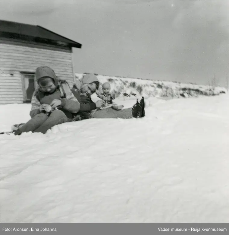 Søstrene Liv-Erna og Joronn leker med dukker på sneskavla i Makkenes. Bildet er tatt på vårparten mars/april og i Vadsø kommune, ca 1965.