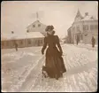 Vintermotiv kvinna med hund, Torggatan vid Stora torget, Enköping, vy från sydöst, ca 1898-1902.