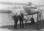 Flygplan FVM S 18, nr 986 vid Flygkompaniets verkstäder på Malmen omkring 1919-1925. Framför flygplanet syns dess konstruktör Henry Kjellson och en officer.