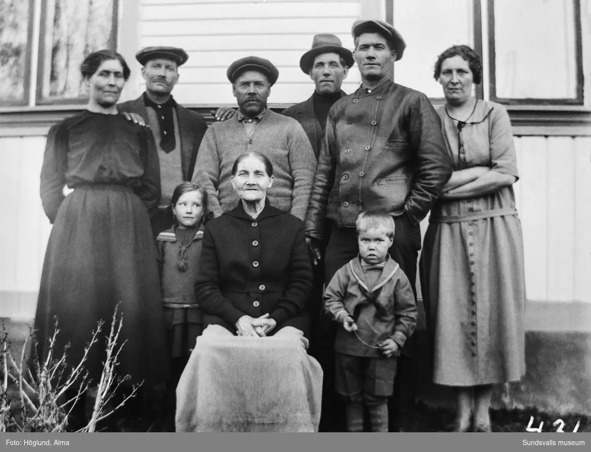 Grupporträtt med familjen Bergman i Fanbyn. Den äldre kvinnan är Märtha Bergman (fotograf Alma Höglunds moster), bakom står fem av hennes barn samt en svärdotter. Till vänster Frida Kristina och Johan Arvid, till höger Amerikafrämmandet Carl Otto och hans fru Bertha samt deras son Carl Otto jr. I mitten står Oscar Nio och Erik Olof.