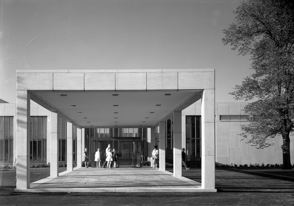 Eksteriørbilde av Munchmuseet i Oslo. Museets inngangsparti sett forfra. Ved inngangen står barn og voksne. Museet er tegnet av arkitektene Gunnar Fougner og Einar Myklebust og åpnet i 1963, hundre år etter kunstnerens fødsel.