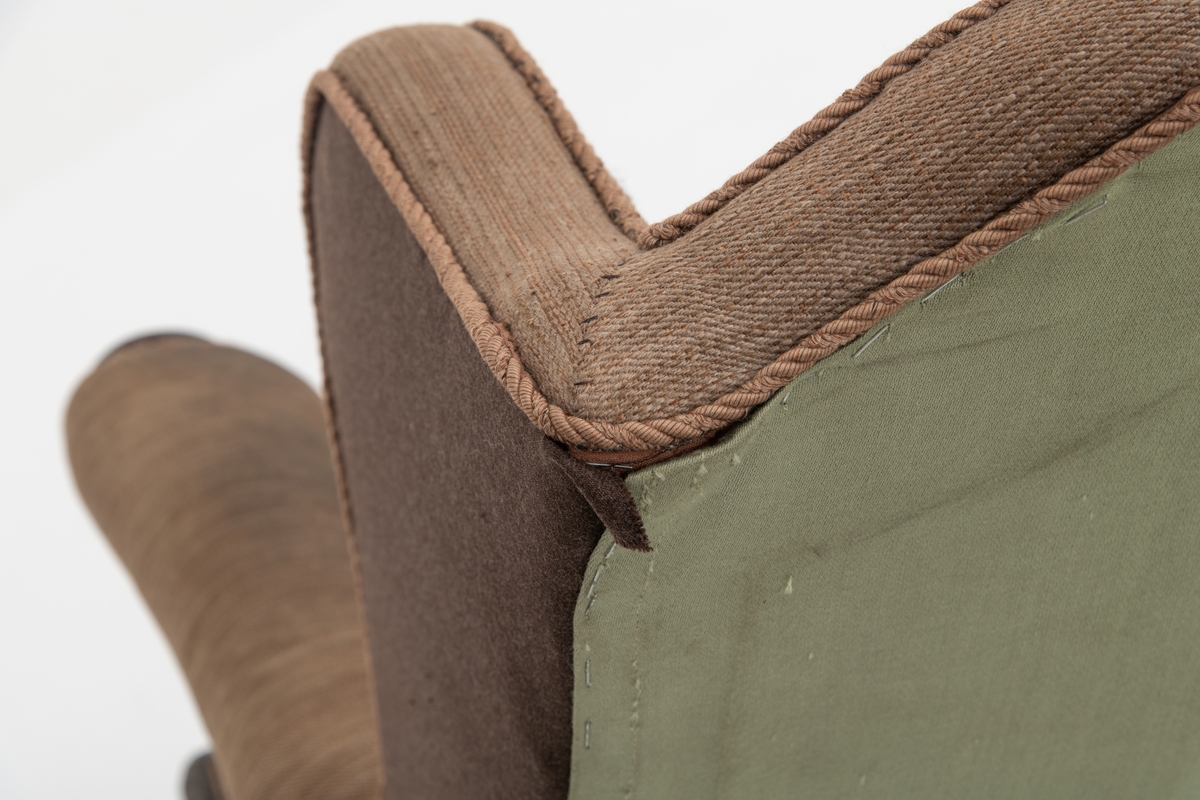 Sofa med trekk vevd av Ulrikke Greve. Vevnaden er vevet spesielt til denne sofaen. Det  er nyere stoff-trekk på armlenene. Møbeltrekket er nå stiftet fast med stiftemaskin; antagelig en reparasjon, og dekorert med pyntestift i messing.