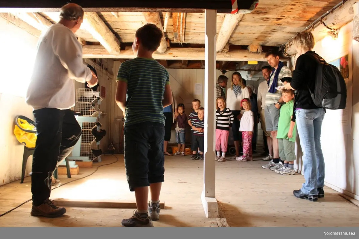 Tor Larsen instruerer i å kaste 'blekkskiv'. Arrangementsfoto fra "Familiedagen" i regi av Nordmøre museum på Milnbrygga, Gomalandet i Kristiansund. Bildet er datert 21. juni 2009. Fotograf er Roar Leite ved Nordmøre museum. Fra Nordmøre museums fotosamlinger.