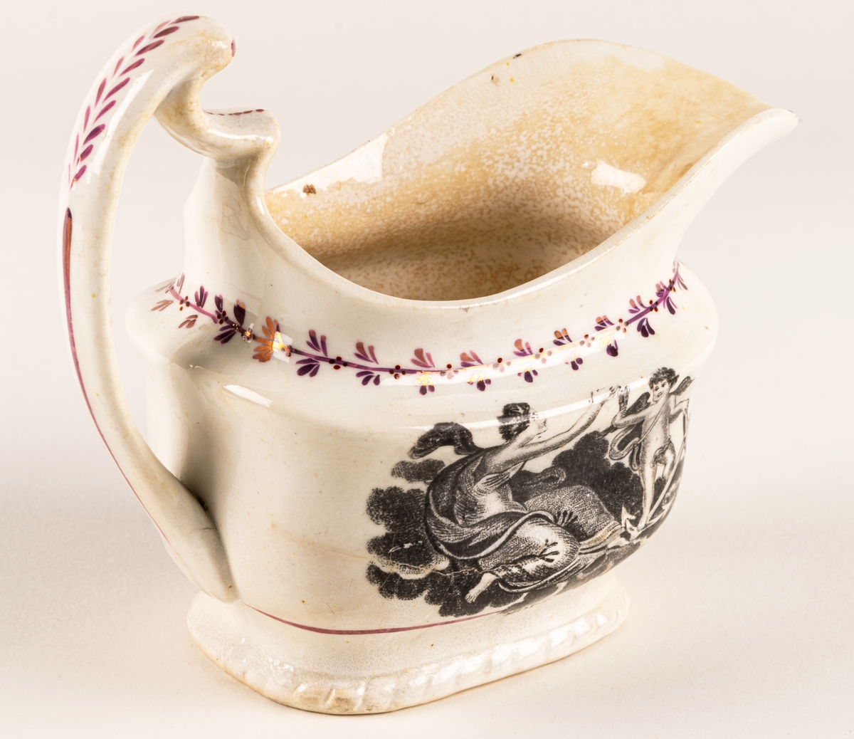 Gräddkanna av engelskt flintgods med rosa lyster. Dekor: allegoriska figurer i svart, samt röda växtband. Text "Faith & Hope".