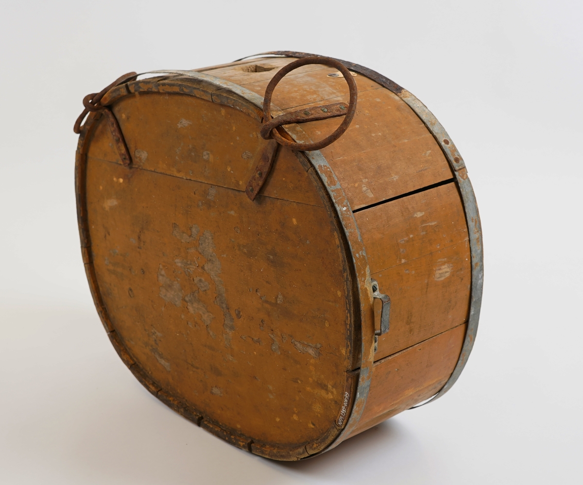 Mjølkeflaske/ kløvflaske. I tre. Oval form. Lagga. To metall band rundt. Måla med okerfarga måling. To jarnringer på eine sida nytta til feste ved bering/ frakting med hest (kløv).