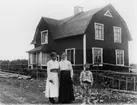 Tvåvånings bostadshus, tre personer framför huset.
Bertil Lindby med mor och mormor.