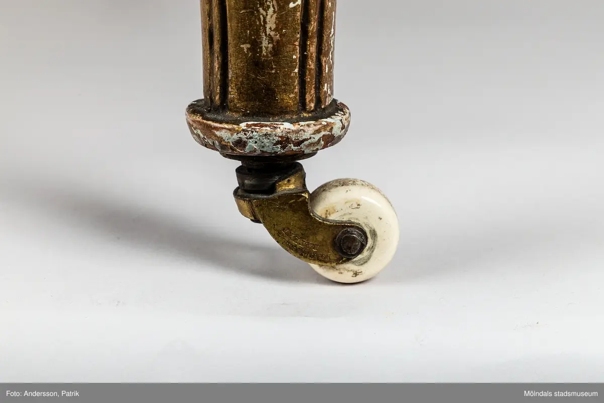 Fåtölj, s.k. "baljfåtölj", sengustaviansk, tillverkad omkring år 1800. 

Kraftigt svängd rygg, raka sarger med skuren dekor, svarvade, bladhölstrade och kannelerade framben, sabelformade bakben. 
Fast stoppad sits och rygg, med sliten, senare klädsel i grönrandigt siden. Bevarad originalstoppning.

Senare bemålning i guld. Äldre rödbrun färg kan anas under förgyllningen.
Benen har kortats av och kompletterats med trissor (hjul) i mässing under 1800-talets andra hälft.

Sitthöjd 440 mm, Bredd 610 mm.
Material: Björk, Tageltyg, Sadelgjord.

Fåtöljen är en av ett par. Båda är signerade med brännstämpel AIS på den bakre sargen. Det finns fyra kända snickare i Lindome som använde signaturen AIS – Anders Johansson i Hassungared (1780-1847), Anders Jonsson i Ingemantorp (1770-1832), Anders Jönsson i Gastorp (1778-1858) och Andreas Johansson i Skår (1793-1871).

Inköpt på Kungsbacka Auktionskammare.
Samhör med MM05442