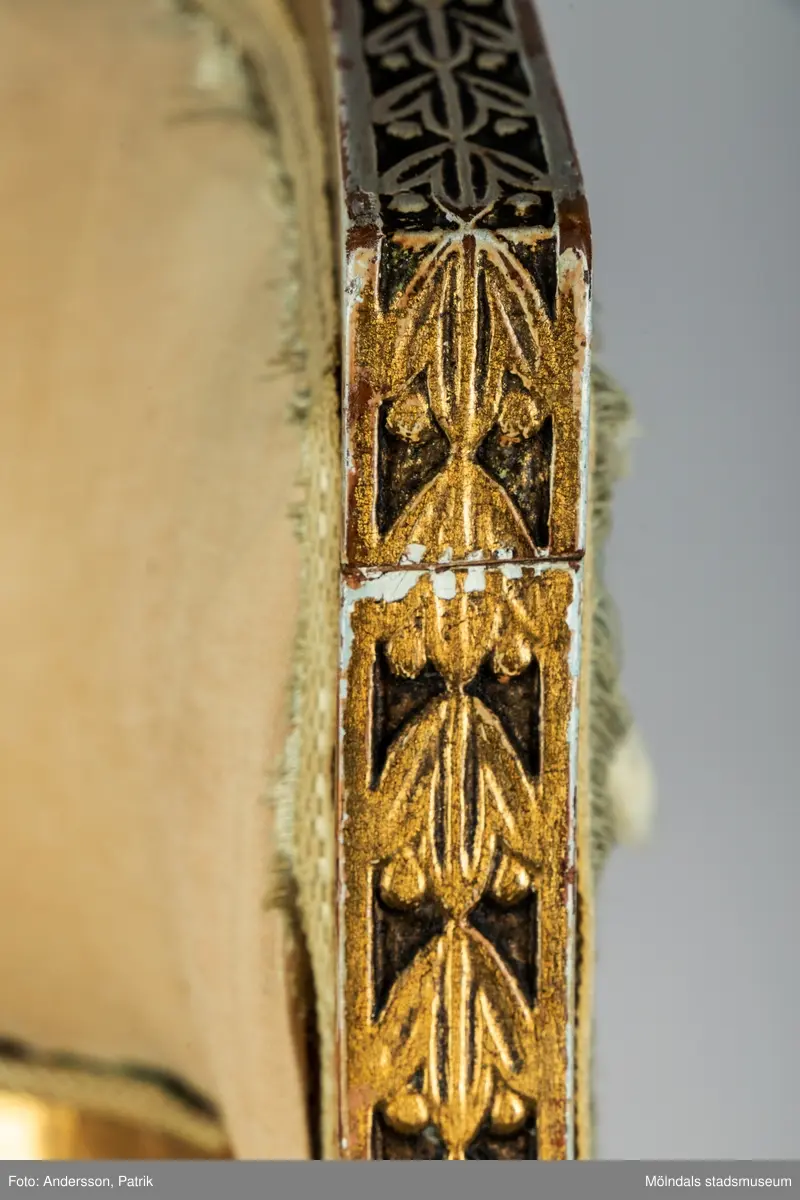 Fåtölj, s.k. "baljfåtölj", sengustaviansk, tillverkad omkring år 1800. 

Kraftigt svängd rygg, raka sarger med skuren dekor, svarvade, bladhölstrade och kannelerade framben, sabelformade bakben. 
Fast stoppad sits och rygg, med sliten, senare klädsel i grönrandigt siden. Bevarad originalstoppning.

Senare bemålning i guld. Äldre rödbrun färg kan anas under förgyllningen.
Benen har kortats av och kompletterats med trissor (hjul) i mässing under 1800-talets andra hälft.

Sitthöjd 440 mm, Bredd 610 mm.
Material: Björk, Tageltyg, Sadelgjord.

Fåtöljen är en av ett par. Båda är signerade med brännstämpel AIS på den bakre sargen. Det finns fyra kända snickare i Lindome som använde signaturen AIS – Anders Johansson i Hassungared (1780-1847), Anders Jonsson i Ingemantorp (1770-1832), Anders Jönsson i Gastorp (1778-1858) och Andreas Johansson i Skår (1793-1871).

Inköpt på Kungsbacka Auktionskammare.
Samhör med MM05442