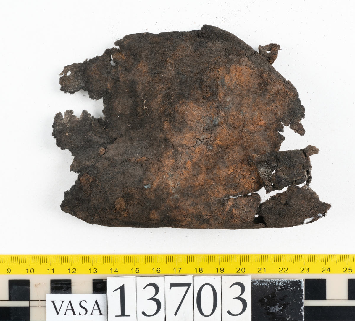 Delar och fragment av sko: ovanläder, skobotten, sula, skopligg samt fragment.

Ovanlädret är fragmentariskt och spaltad samt har rostfärgade utfällningar.

Skobottnen har kvarsittande skopligg och tråd. Klacken är uppbyggd av tre eller fyra klacklappar. Lädret har en grå beläggning, troligtvis av lera, samt rostfärgade utfällningar.

En sula med kvarsittande tråd. Lädret till sulan är kraftig.

Totalt fyra löst liggande skopligg och nio fragment/delar.