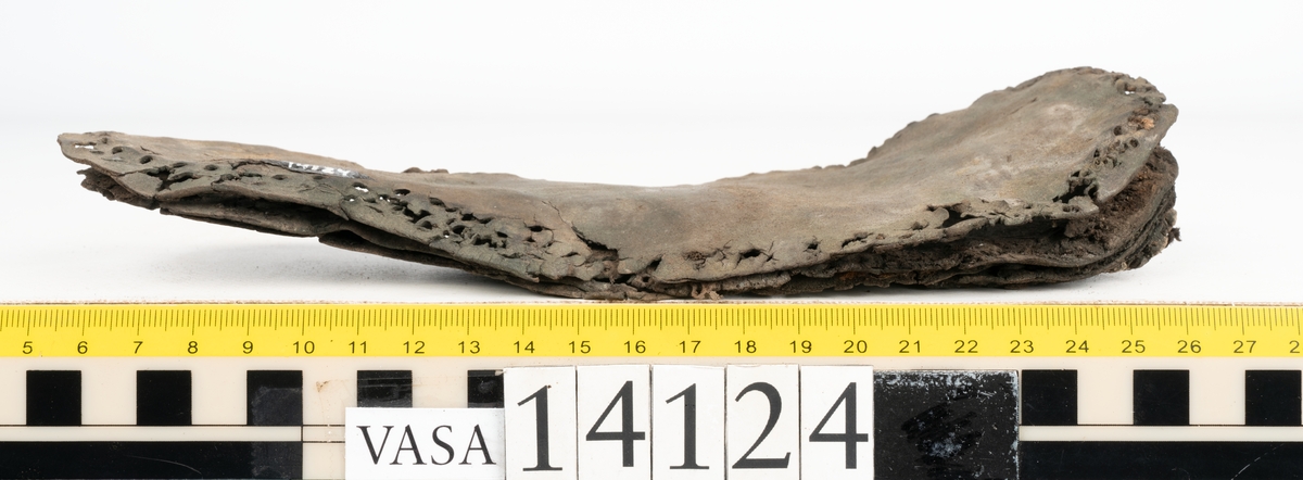 Sandalsydd högersko, troligtvis toffel, i delar.

Skobottnen består av två sulor med kvarsittanda skopligg och tråd. Vid tåpartiet sitter laglappar. På undersidan av yttersulan syns rostfärgade utfällningar.

Elva fragment från bottnen: sulor m m.

Ett fragmentariskt ovanläder. Ovanlädret har vita och rostfärgade utfällningar samt ligger hopvikt. Lädret är mycket sprött.
Totalt 15 fragment.