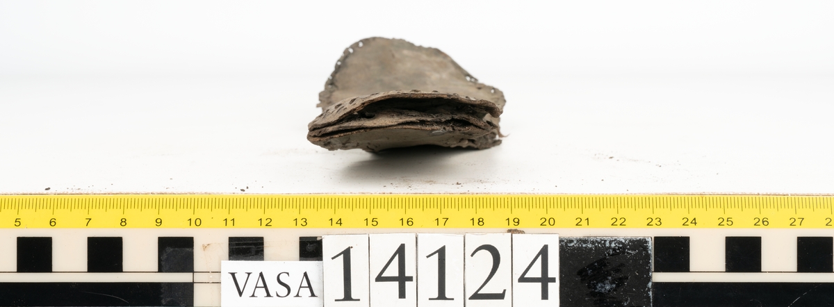 Sandalsydd högersko, troligtvis toffel, i delar.

Skobottnen består av två sulor med kvarsittanda skopligg och tråd. Vid tåpartiet sitter laglappar. På undersidan av yttersulan syns rostfärgade utfällningar.

Elva fragment från bottnen: sulor m m.

Ett fragmentariskt ovanläder. Ovanlädret har vita och rostfärgade utfällningar samt ligger hopvikt. Lädret är mycket sprött.
Totalt 15 fragment.