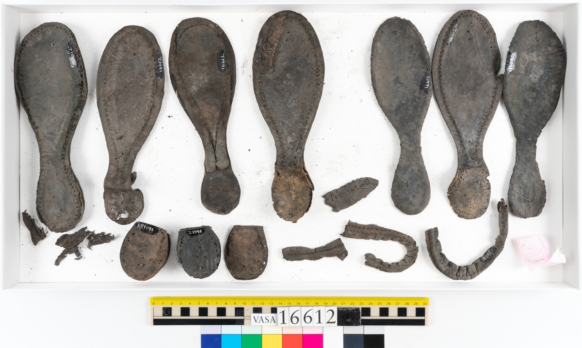 Delar och fragment av två skobottnar till höger- och vänstersko. Totalt 18 delar och fragment.
Sju sulor med kvarsittande tråd. Sulornas längd varierar mellan 220-230 mm, största bredden varierar mellan 65-75 mm, minsta bredden mellan 25-35 mm och hälbredden mellan 45-50 mm. Lädret till sulorna är kraftigt.
Klackar 16612 samt 16612:1 består av vardera fem klacklappar med kvarsittandskopligg. Klacklapparna är spaltade. I materialet finns en löst liggande klacklapp som tillhör klack 16621:1.
Tre delar holtrand med kvarsittande tråd.
Tre fragment från skobotten.