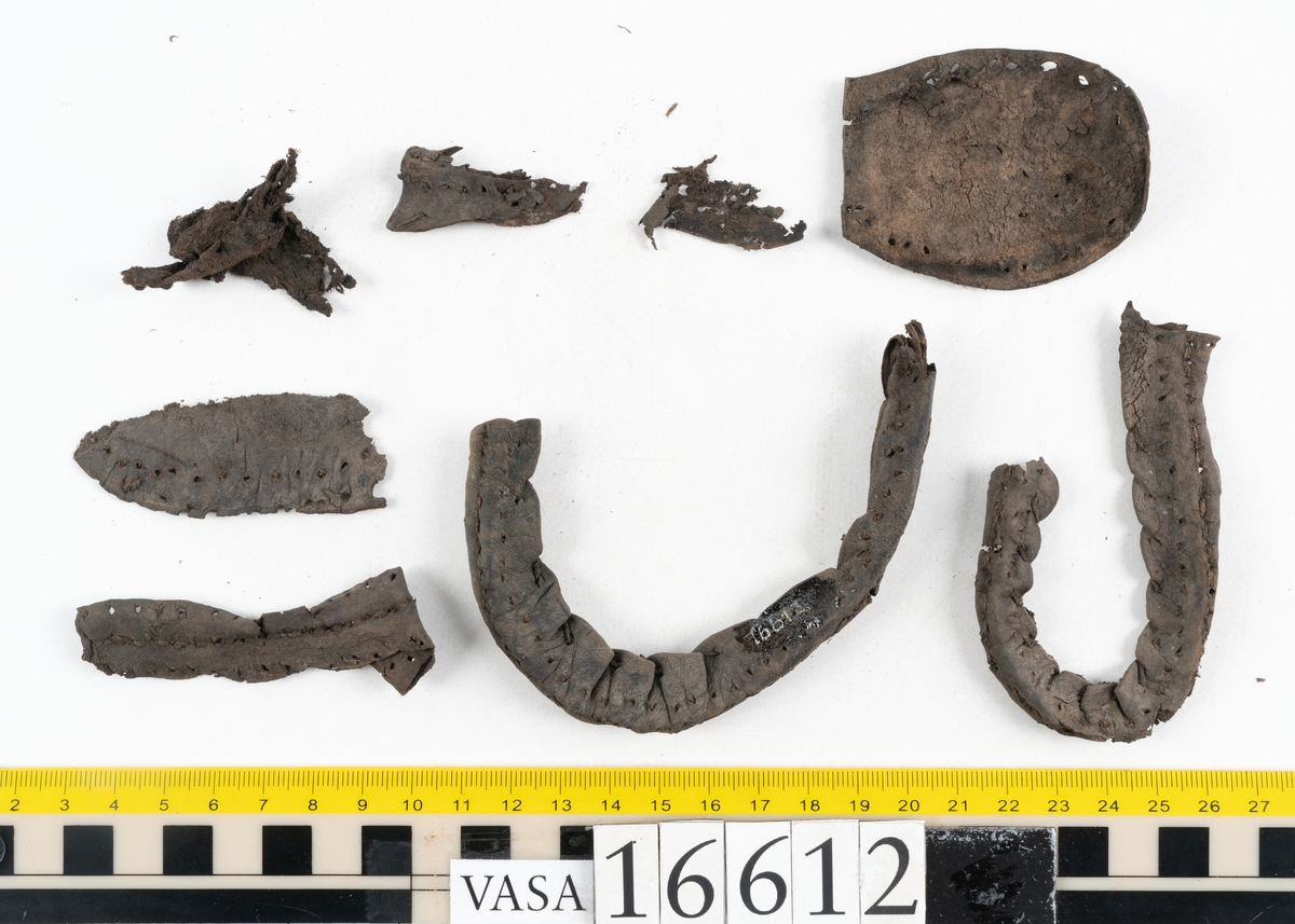 Delar och fragment av två skobottnar till höger- och vänstersko. Totalt 18 delar och fragment.
Sju sulor med kvarsittande tråd. Sulornas längd varierar mellan 220-230 mm, största bredden varierar mellan 65-75 mm, minsta bredden mellan 25-35 mm och hälbredden mellan 45-50 mm. Lädret till sulorna är kraftigt.
Klackar 16612 samt 16612:1 består av vardera fem klacklappar med kvarsittandskopligg. Klacklapparna är spaltade. I materialet finns en löst liggande klacklapp som tillhör klack 16621:1.
Tre delar holtrand med kvarsittande tråd.
Tre fragment från skobotten.