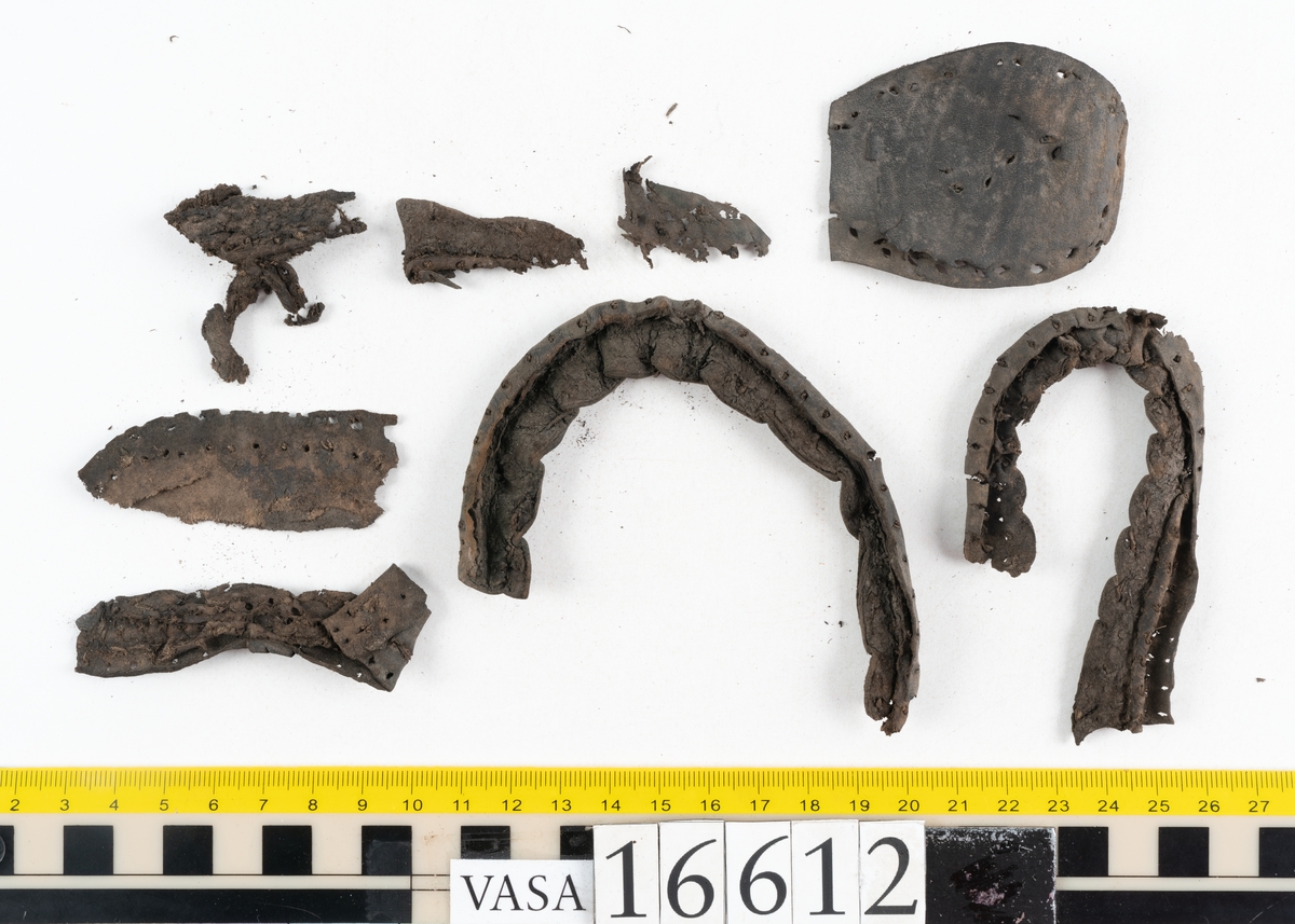 Delar och fragment av två skobottnar till höger- och vänstersko. Totalt 18 delar och fragment.
Sju sulor med kvarsittande tråd. Sulornas längd varierar mellan 220-230 mm, största bredden varierar mellan 65-75 mm, minsta bredden mellan 25-35 mm och hälbredden mellan 45-50 mm. Lädret till sulorna är kraftigt.
Klackar 16612 samt 16612:1 består av vardera fem klacklappar med kvarsittandskopligg. Klacklapparna är spaltade. I materialet finns en löst liggande klacklapp som tillhör klack 16621:1.
Tre delar holtrand med kvarsittande tråd.
Tre fragment från skobotten.