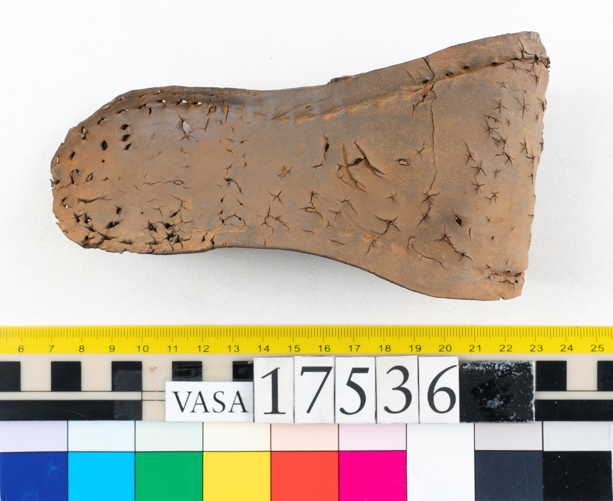 Sula med kantigt format tåparti. Sulan är täckt av kvarsittande skopligg samt hål efter skopligg. På sulans köttsida löper stygnshål. Sulan ligger vikt.
Lädret är kraftigt.