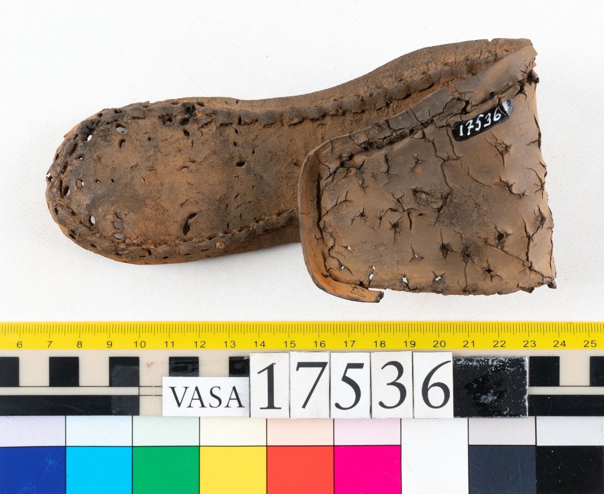 Sula med kantigt format tåparti. Sulan är täckt av kvarsittande skopligg samt hål efter skopligg. På sulans köttsida löper stygnshål. Sulan ligger vikt.
Lädret är kraftigt.