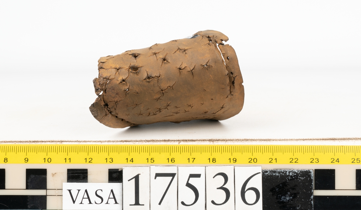 Sula med kantigt format tåparti. Sulan är täckt av kvarsittande skopligg samt hål efter skopligg. På sulans köttsida löper stygnshål. Sulan ligger vikt.
Lädret är kraftigt.