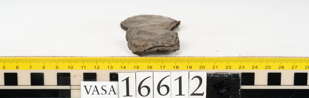 Delar och fragment av två skobottnar till höger- och vänstersko. Totalt 18 delar och fragment.
Sju sulor med kvarsittande tråd. Sulornas längd varierar mellan 220-230 mm, största bredden varierar mellan 65-75 mm, minsta bredden mellan 25-35 mm och hälbredden mellan 45-50 mm. Lädret till sulorna är kraftigt.
Klackar 16612 samt 16612:1 består av vardera fem klacklappar med kvarsittandskopligg. Klacklapparna är spaltade. I materialet finns en löst liggande klacklapp som tillhör klack 16621:1.
Tre delar holtrand med kvarsittande tråd.
Tre fragment från skobotten.