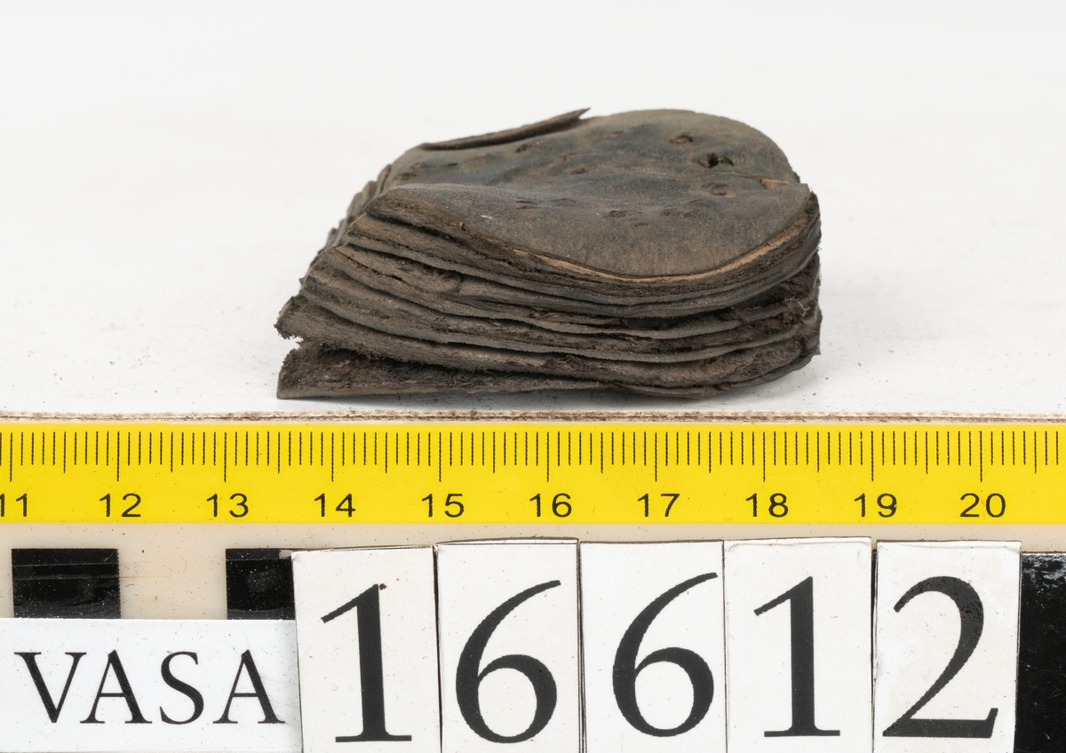 Delar och fragment av två skobottnar till höger- och vänstersko. Totalt 18 delar och fragment.
Sju sulor med kvarsittande tråd. Sulornas längd varierar mellan 220-230 mm, största bredden varierar mellan 65-75 mm, minsta bredden mellan 25-35 mm och hälbredden mellan 45-50 mm. Lädret till sulorna är kraftigt.
Klackar 16612 samt 16612:1 består av vardera fem klacklappar med kvarsittandskopligg. Klacklapparna är spaltade. I materialet finns en löst liggande klacklapp som tillhör klack 16621:1.
Tre delar holtrand med kvarsittande tråd.
Tre fragment från skobotten.