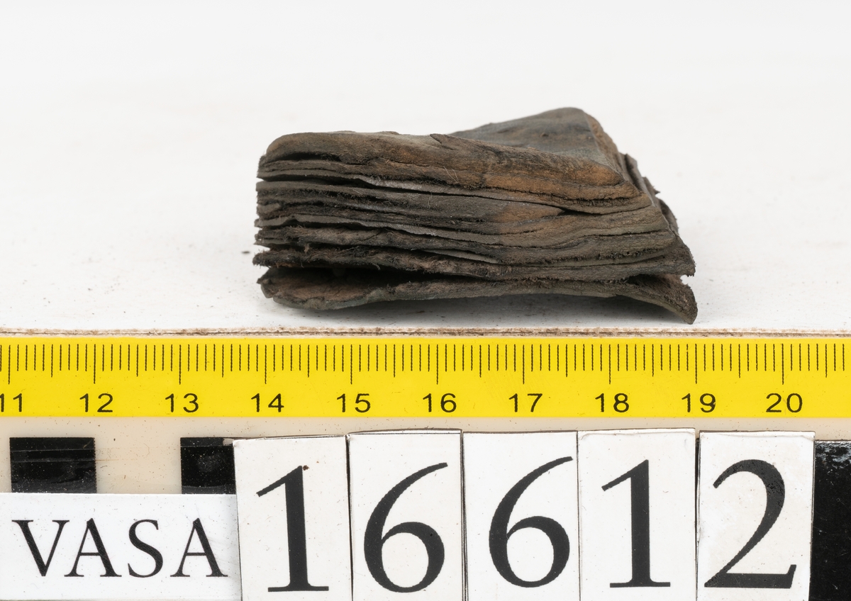 Delar och fragment av två skobottnar till höger- och vänstersko. Totalt 18 delar och fragment.
Sju sulor med kvarsittande tråd. Sulornas längd varierar mellan 220-230 mm, största bredden varierar mellan 65-75 mm, minsta bredden mellan 25-35 mm och hälbredden mellan 45-50 mm. Lädret till sulorna är kraftigt.
Klackar 16612 samt 16612:1 består av vardera fem klacklappar med kvarsittandskopligg. Klacklapparna är spaltade. I materialet finns en löst liggande klacklapp som tillhör klack 16621:1.
Tre delar holtrand med kvarsittande tråd.
Tre fragment från skobotten.