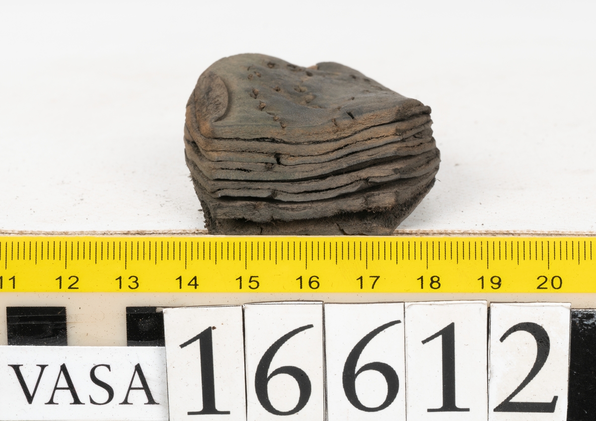Delar och fragment av två skobottnar till höger- och vänstersko. Totalt 18 delar och fragment.
Sju sulor med kvarsittande tråd. Sulornas längd varierar mellan 220-230 mm, största bredden varierar mellan 65-75 mm, minsta bredden mellan 25-35 mm och hälbredden mellan 45-50 mm. Lädret till sulorna är kraftigt.
Klackar 16612 samt 16612:1 består av vardera fem klacklappar med kvarsittandskopligg. Klacklapparna är spaltade. I materialet finns en löst liggande klacklapp som tillhör klack 16621:1.
Tre delar holtrand med kvarsittande tråd.
Tre fragment från skobotten.
