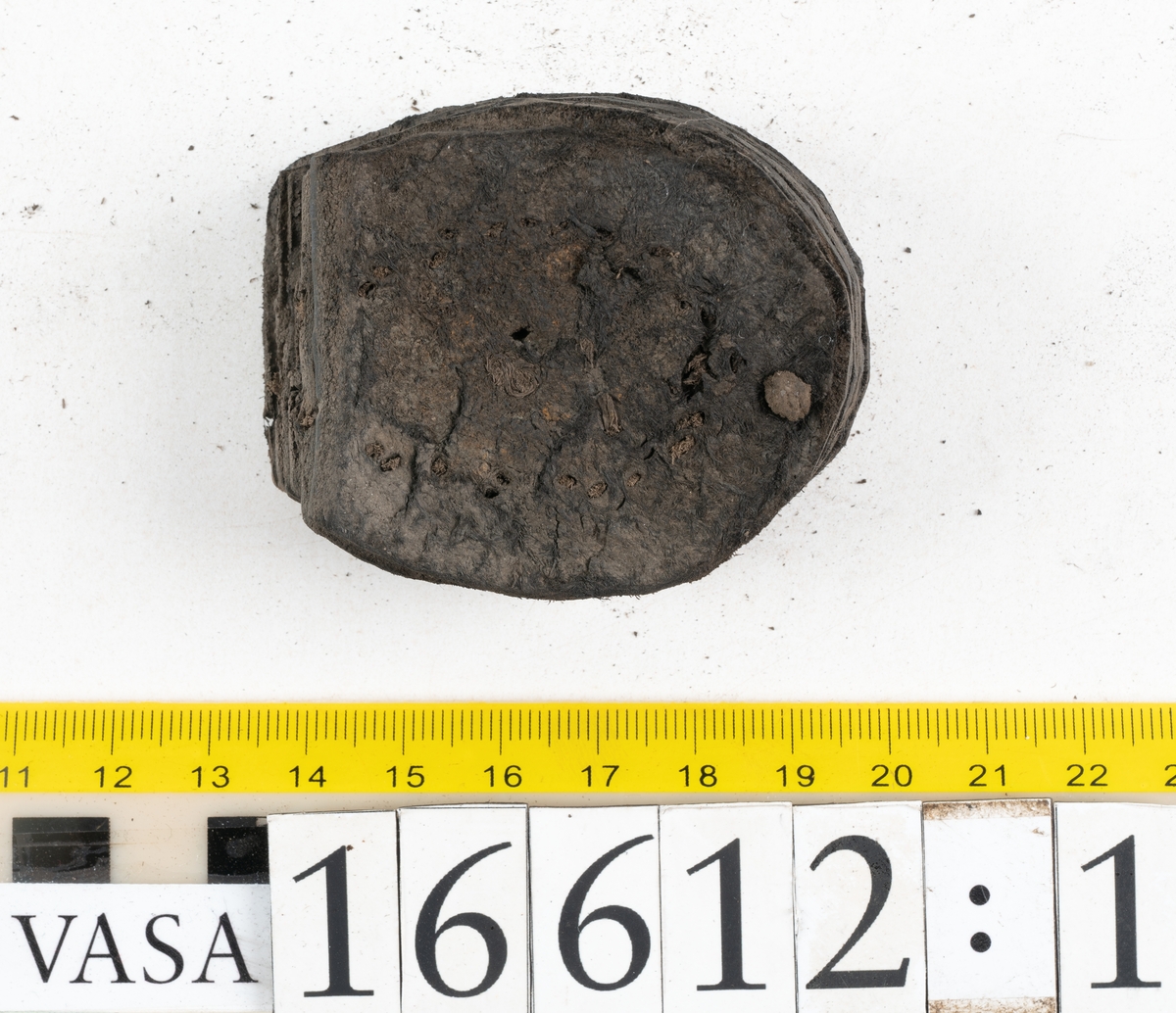 Delar och fragment av två skobottnar till höger- och vänstersko. Totalt 18 delar och fragment.
Sju sulor med kvarsittande tråd. Sulornas längd varierar mellan 220-230 mm, största bredden varierar mellan 65-75 mm, minsta bredden mellan 25-35 mm och hälbredden mellan 45-50 mm. Lädret till sulorna är kraftigt.
Klackar 16612 samt 16612:1 består av vardera fem klacklappar med kvarsittandskopligg. Klacklapparna är spaltade. I materialet finns en löst liggande klacklapp som tillhör klack 16621:1.
Tre delar holtrand med kvarsittande tråd.
Tre fragment från skobotten.