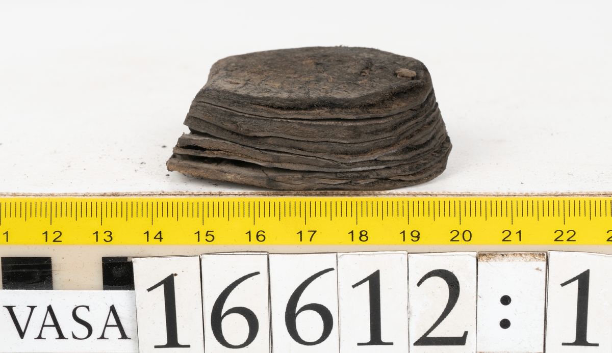 Delar och fragment av två skobottnar till höger- och vänstersko. Totalt 18 delar och fragment.
Sju sulor med kvarsittande tråd. Sulornas längd varierar mellan 220-230 mm, största bredden varierar mellan 65-75 mm, minsta bredden mellan 25-35 mm och hälbredden mellan 45-50 mm. Lädret till sulorna är kraftigt.
Klackar 16612 samt 16612:1 består av vardera fem klacklappar med kvarsittandskopligg. Klacklapparna är spaltade. I materialet finns en löst liggande klacklapp som tillhör klack 16621:1.
Tre delar holtrand med kvarsittande tråd.
Tre fragment från skobotten.