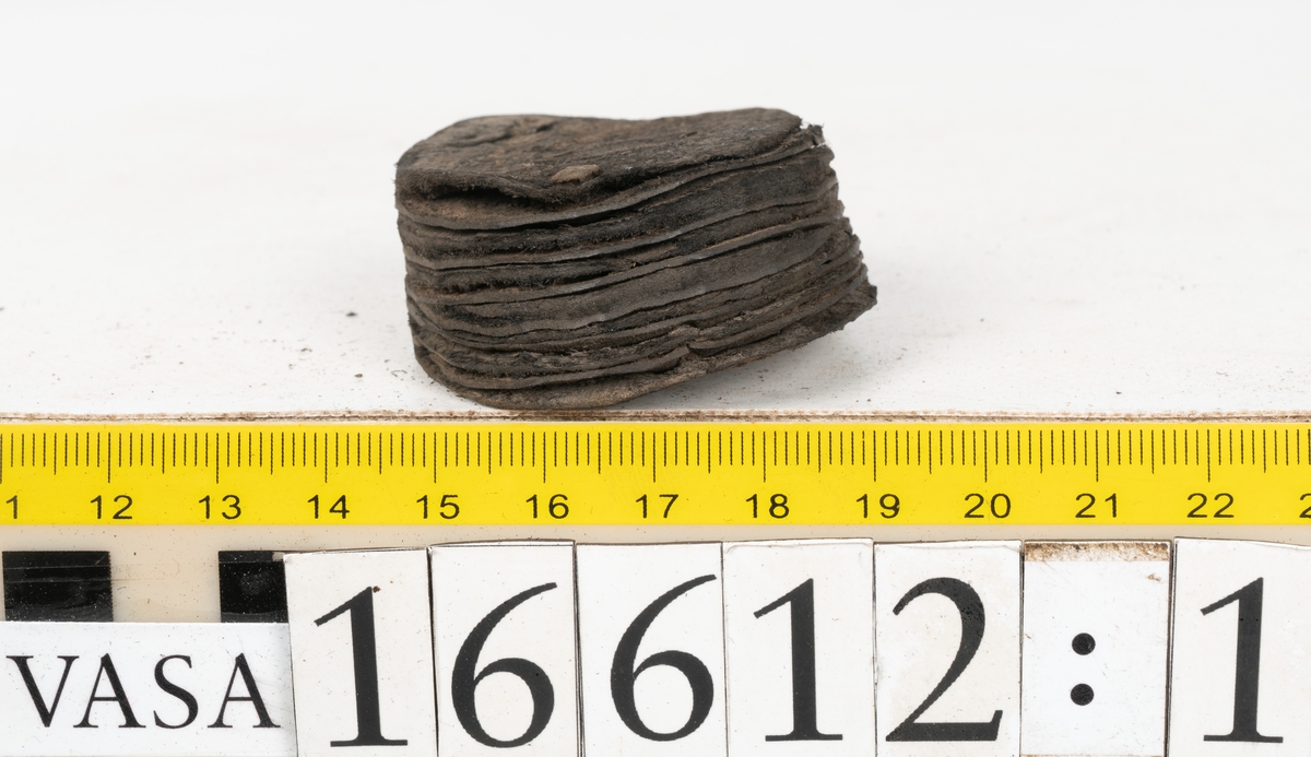 Delar och fragment av två skobottnar till höger- och vänstersko. Totalt 18 delar och fragment.
Sju sulor med kvarsittande tråd. Sulornas längd varierar mellan 220-230 mm, största bredden varierar mellan 65-75 mm, minsta bredden mellan 25-35 mm och hälbredden mellan 45-50 mm. Lädret till sulorna är kraftigt.
Klackar 16612 samt 16612:1 består av vardera fem klacklappar med kvarsittandskopligg. Klacklapparna är spaltade. I materialet finns en löst liggande klacklapp som tillhör klack 16621:1.
Tre delar holtrand med kvarsittande tråd.
Tre fragment från skobotten.