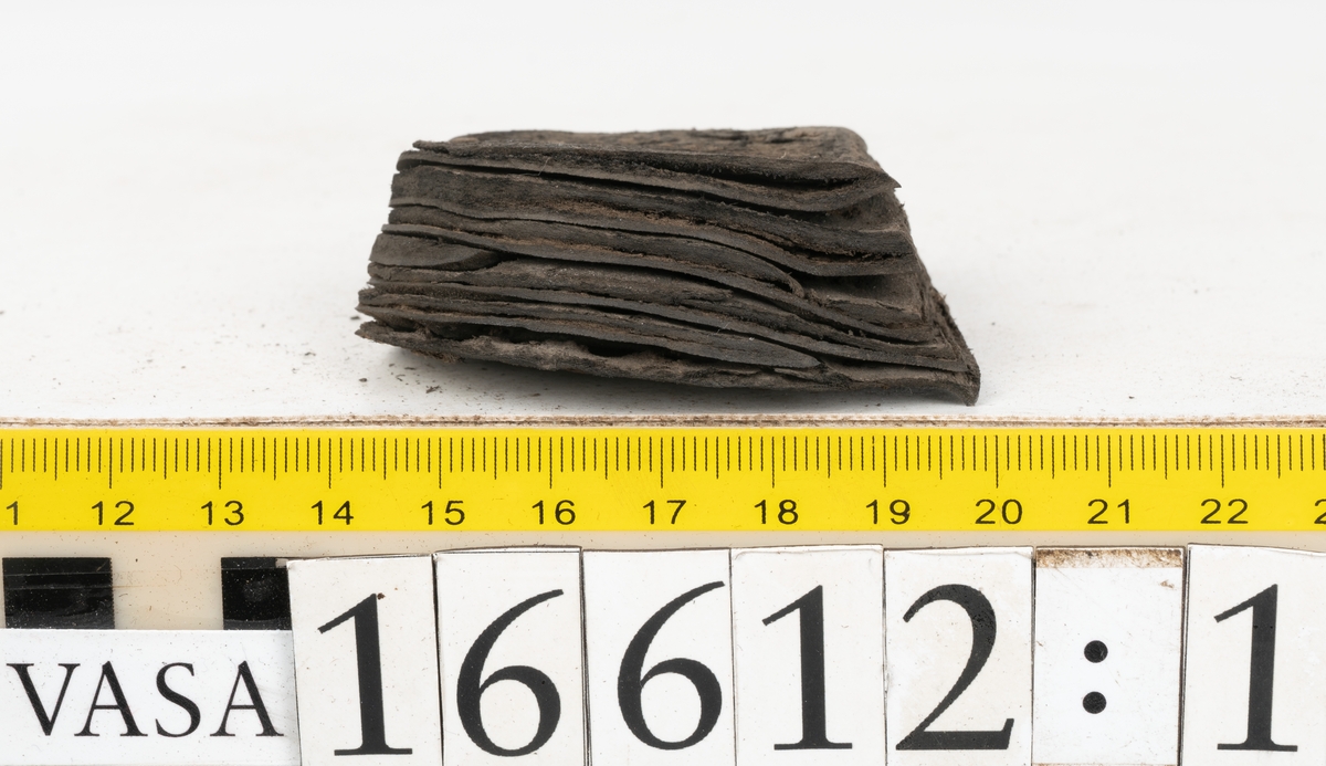 Delar och fragment av två skobottnar till höger- och vänstersko. Totalt 18 delar och fragment.
Sju sulor med kvarsittande tråd. Sulornas längd varierar mellan 220-230 mm, största bredden varierar mellan 65-75 mm, minsta bredden mellan 25-35 mm och hälbredden mellan 45-50 mm. Lädret till sulorna är kraftigt.
Klackar 16612 samt 16612:1 består av vardera fem klacklappar med kvarsittandskopligg. Klacklapparna är spaltade. I materialet finns en löst liggande klacklapp som tillhör klack 16621:1.
Tre delar holtrand med kvarsittande tråd.
Tre fragment från skobotten.