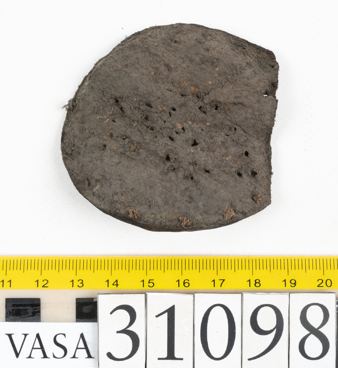 Dokumentation 1997:
Tre delar av sko: en del av en skobotten, en klacklapp och ett ovanläder samt två fragment som lossnat från dessa.
Del av skobotten i form av en yttersula med kvarsittande klack. Klacken är uppbyggd av 5-6 klacklappar. Sulans undersida är ritsad. Sulan är spaltad och tåpartiet är fragmentarisk. Sulan och klacken har kvarsittande träpligg.
En klacklapp med kvarsittande träpligg. Runt ytterkanterna och i klacklappens mitt finns hål efter träpligg.
Ett ovanläder samt en lös bit av plösen. På den lösa biten finns två snörhål. Längs med ovanlädrets ytterkanter löper stygnshål. Köttsidan har börjat att släppa från narvsidan.

Dokumentation 2022:
Del av ovanläder. Framstycke till en öppen svensksko som består av fragment. Tillverkad i läder. Inga dekorationer. Tillhörde en sko som bars på vänster fot. Ovanligt spetsig tå-del. Plösen är skadad och saknas. Det finns delaminering och veckning och inga tecken på lagningar. Det finns en tillhörande klack.
För mer information, se Länkade filer: Uppritning

Text in english:
This is the vamp of an open latchet shoe, made of leather, of stitch-down construction, worn on the left foot, with no decorative features, and an unusually pointed toe. The vamp consists of fragments, with the tongue broken off, and has suffered delamination and creasing. There are no signs of repairs. There is a heel associated with the vamp.
For more information, go to Länkade filer: Uppritning