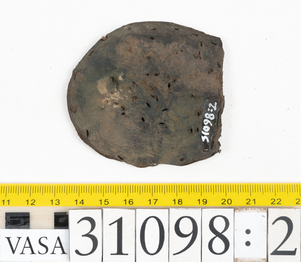Dokumentation 1997:
Tre delar av sko: en del av en skobotten, en klacklapp och ett ovanläder samt två fragment som lossnat från dessa.
Del av skobotten i form av en yttersula med kvarsittande klack. Klacken är uppbyggd av 5-6 klacklappar. Sulans undersida är ritsad. Sulan är spaltad och tåpartiet är fragmentarisk. Sulan och klacken har kvarsittande träpligg.
En klacklapp med kvarsittande träpligg. Runt ytterkanterna och i klacklappens mitt finns hål efter träpligg.
Ett ovanläder samt en lös bit av plösen. På den lösa biten finns två snörhål. Längs med ovanlädrets ytterkanter löper stygnshål. Köttsidan har börjat att släppa från narvsidan.

Dokumentation 2022:
Del av ovanläder. Framstycke till en öppen svensksko som består av fragment. Tillverkad i läder. Inga dekorationer. Tillhörde en sko som bars på vänster fot. Ovanligt spetsig tå-del. Plösen är skadad och saknas. Det finns delaminering och veckning och inga tecken på lagningar. Det finns en tillhörande klack.
För mer information, se Länkade filer: Uppritning

Text in english:
This is the vamp of an open latchet shoe, made of leather, of stitch-down construction, worn on the left foot, with no decorative features, and an unusually pointed toe. The vamp consists of fragments, with the tongue broken off, and has suffered delamination and creasing. There are no signs of repairs. There is a heel associated with the vamp.
For more information, go to Länkade filer: Uppritning
