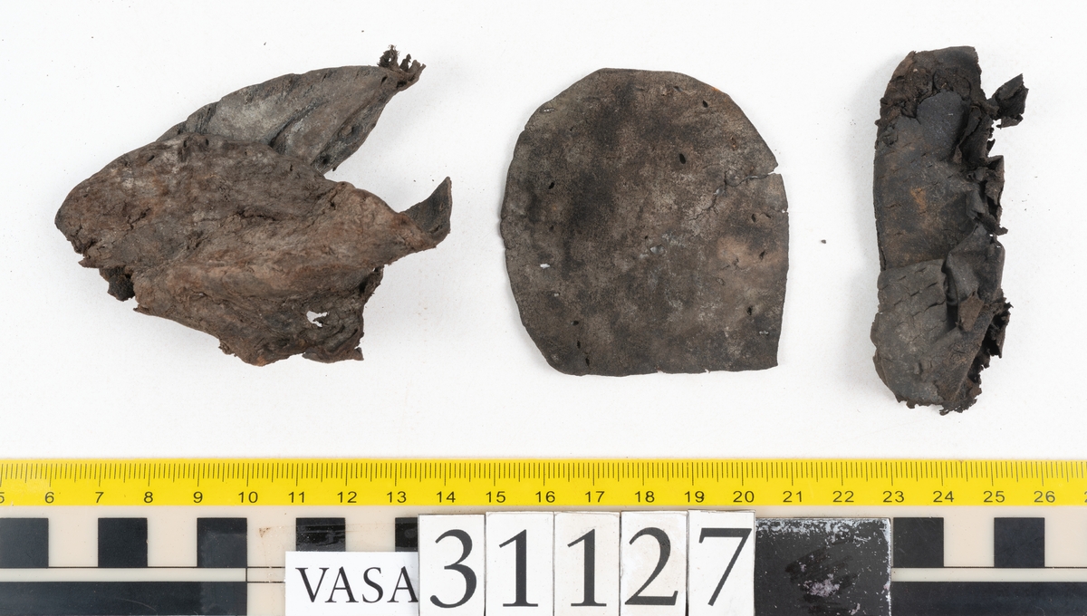 Delar och fragment från sko: tre sulor, en holtrand, en klacklapp, en klacklapp eller ett inlägg samt ett 40-tal delar och mindre fragment från skoöverdel och skobotten.

Sula fyndnummer 31127 har kvarsittande tråd. På sulans ovansida finns intryck av bindtråden.  Sula fyndnummer 31127:1 har kvarsittande träpligg och tråd. I tåpartiet finns en laglapp. Sulans hälparti är avskuret, eventuellt avbrutet.  Sula fyndnummer 31127:2 har ett fragmentariskt hälparti. På sulans ovansida finns intryck av bindtråd. Holtrand fyndnummer 31127:3 har kvarsittande tråd. På klacklapp fyndnummer 31127:4 finns hål efter träpligg. På klacklapp, eventuellt inlägg, fyndnummer 31127:5 finns kvarsittande tråd.