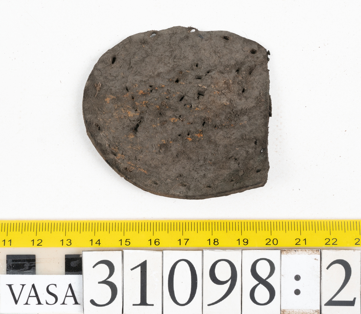 Dokumentation 1997:
Tre delar av sko: en del av en skobotten, en klacklapp och ett ovanläder samt två fragment som lossnat från dessa.
Del av skobotten i form av en yttersula med kvarsittande klack. Klacken är uppbyggd av 5-6 klacklappar. Sulans undersida är ritsad. Sulan är spaltad och tåpartiet är fragmentarisk. Sulan och klacken har kvarsittande träpligg.
En klacklapp med kvarsittande träpligg. Runt ytterkanterna och i klacklappens mitt finns hål efter träpligg.
Ett ovanläder samt en lös bit av plösen. På den lösa biten finns två snörhål. Längs med ovanlädrets ytterkanter löper stygnshål. Köttsidan har börjat att släppa från narvsidan.

Dokumentation 2022:
Del av ovanläder. Framstycke till en öppen svensksko som består av fragment. Tillverkad i läder. Inga dekorationer. Tillhörde en sko som bars på vänster fot. Ovanligt spetsig tå-del. Plösen är skadad och saknas. Det finns delaminering och veckning och inga tecken på lagningar. Det finns en tillhörande klack.
För mer information, se Länkade filer: Uppritning

Text in english:
This is the vamp of an open latchet shoe, made of leather, of stitch-down construction, worn on the left foot, with no decorative features, and an unusually pointed toe. The vamp consists of fragments, with the tongue broken off, and has suffered delamination and creasing. There are no signs of repairs. There is a heel associated with the vamp.
For more information, go to Länkade filer: Uppritning
