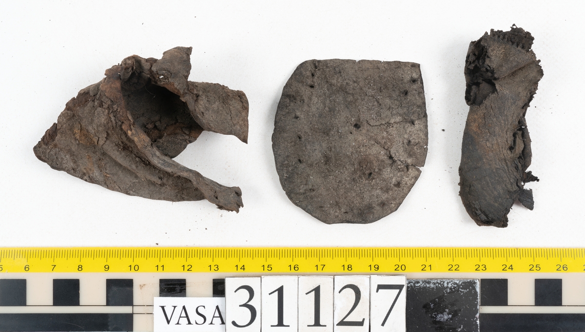 Delar och fragment från sko: tre sulor, en holtrand, en klacklapp, en klacklapp eller ett inlägg samt ett 40-tal delar och mindre fragment från skoöverdel och skobotten.

Sula fyndnummer 31127 har kvarsittande tråd. På sulans ovansida finns intryck av bindtråden.  Sula fyndnummer 31127:1 har kvarsittande träpligg och tråd. I tåpartiet finns en laglapp. Sulans hälparti är avskuret, eventuellt avbrutet.  Sula fyndnummer 31127:2 har ett fragmentariskt hälparti. På sulans ovansida finns intryck av bindtråd. Holtrand fyndnummer 31127:3 har kvarsittande tråd. På klacklapp fyndnummer 31127:4 finns hål efter träpligg. På klacklapp, eventuellt inlägg, fyndnummer 31127:5 finns kvarsittande tråd.