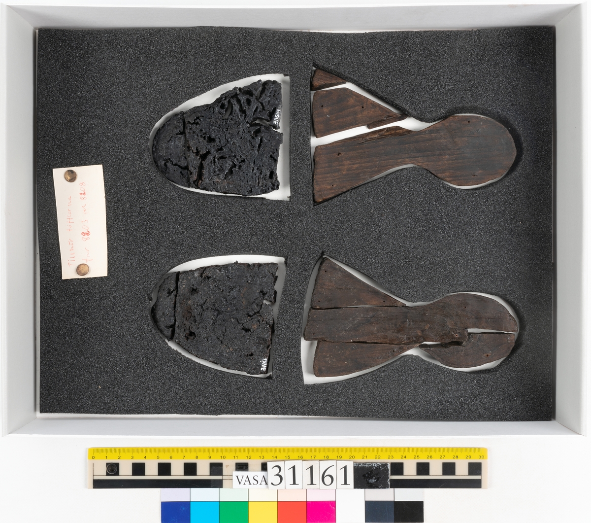 Dokumentation 1998:
Två skobottnar till ett par skor.
Skobottnarna är nu monterade till sko 08208.
Skobottnarna är i fyra delar, två delar från skobottnarnas främre parti, fyndnummer 31161 och 31161:1 och två delar från skobottnarnas bakre parti, fyndnummer 31161:2 samt 31161:3.  De båda bakre partierna, från hälen till partiet efter hålfoten, är tillverkade i trä, troligtvis lövträ. De båda främre partierna, från partiet efter hålfoten och fram till tåpartiet, är tillverkade i kork. Vänster skobotten består troligtvis av fyndnummer 31161:2 och 31161 medan höger skobotten består av fyndnummer 31161:1 och 31161:3.
Bottnarnas främre och bakre partier har spruckit. Träet och korken är täckta med ett lager av polyetylenglykol.

Dokumentation 2022:
Ett par utfyllnader till tofflor. Tillverkade i kork och trä, eventuellt al. Den ena skapades för höger fot och den andra för vänster fot. Korken har blivit bortskuren. Det finns delar som saknas vid tårna och det finns tecken på lagningar med träpligg på hälen. 
För mer information, se Länkade filer: Uppritning

Text in english:
These are a pair of pantable fills, made of cork and wood, possibly alder, made left and right. The cork has been cut and pieced at the toes, there are signs of pegged repairs at the heel.
For more information, go to Länkade filer: Uppritning
