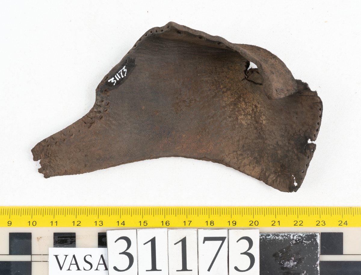 Dokumentation 1998:
Fem delar av överdelen till en slejfsko.
Ett ovanläder med bred och kantigt skuren plös, fyndnummer 31173. Längs med ovanlädrets ena sida och tvärs över tåpartiet löper stygnshål. Längs med ytterkanterna löper hål efter träpligg och stygn. Ovanlädrets främre parti och plös är något fragmentarsika. Lädret är kraftigt med fläckvisa, rostfärgade utfällningar.
En skuren läderremsa, fyndnummer 31173. Remsan har suttit fästad längs ovanlädrets ena sida. Längs med remsans ytterkanter löper hål efter stygn och träpligg.
Två stycken sidostycken med slejf. Sidostyckena har slutit om hälpartiet och fästats samman med en söm mitt bak på skon. Det vänsta sidostycket, fyndnummer 31173:1, är det bäst bevarade. I slejfänden finns ett urtag, troligtvis ett knapphål. Längs med ytterkanterna löper hål efter stygn. Längs den nedre kanten löper hål efter träpligg. Det högra sidostyckets nedre del samt slejfände är fragmentarisk. Lädret är kraftigt och relativt välbevarat.
En förstärkning, fyndnummer 31173:2. Troligtvis har lädret suttit fästat på ovanlädret och förstärkt tåpartiet. Lädret är kraftigt.

Dokumentation 2022:
Del av ovanläder. Framstycke till en sluten sko. Skapades på en rak läst och bars på vänster fot. Inga dekorationer. Fyndnummer 31173:1 är skons bakkappa och den har skador som liknar de från fyndnummer 09806. Fyndnummer 31173:3 är skons sidofoder. Ovanlädrets framstycke och bakkappan saknar vissa fragment och det finns tecken på förstärkningar. Ovanlädrets framstycke har haft förstärkningar på sidans insida och på tån, men de saknas idag. 
För mer information, se Länkade filer: Uppritning

Text in english:
These are a vamp and a quarter of a shoe, made of leather, made on a straight last and worn on the left foot, with no decorative features. 31173:1 represents the quarter and has suffered damage similar to 09805, 31173:3 represents the side lining. There are missing fragments from the vamp and the quarter and there are signs of reinforcements. The vamp had internal reinforcement (missing) only on its lateral side and at the toe.
For more information, go to Länkade filer: Uppritning