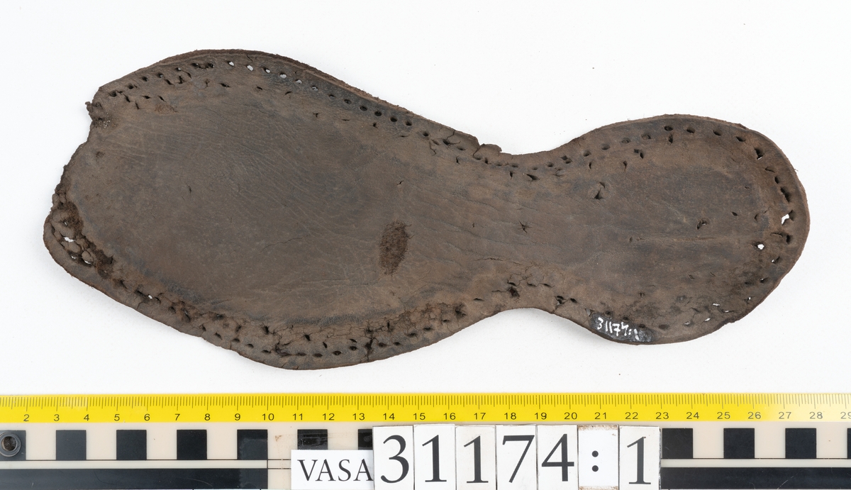 Delar av skobotten.
En sula med kvarsittande del av klacken. Sulan ligger vikt samt är delvis fragmentarisk. Längs med ytterkanterna löper hål efter stygn. Klacken består av fyra klacklappar. Två klacklappar är mycket fragmentariska. Klacken har kvarsittande tråd och träpligg.
En sula. Längs med ytterkanterna löper hål efter träpligg och stygn. Tåpartiet är något fragmentariskt. Lädret är mycket kraftigt.
En klacklapp. Klacklappen är något hästskoformad. På klacklappen syns stora hål efter träpligg.