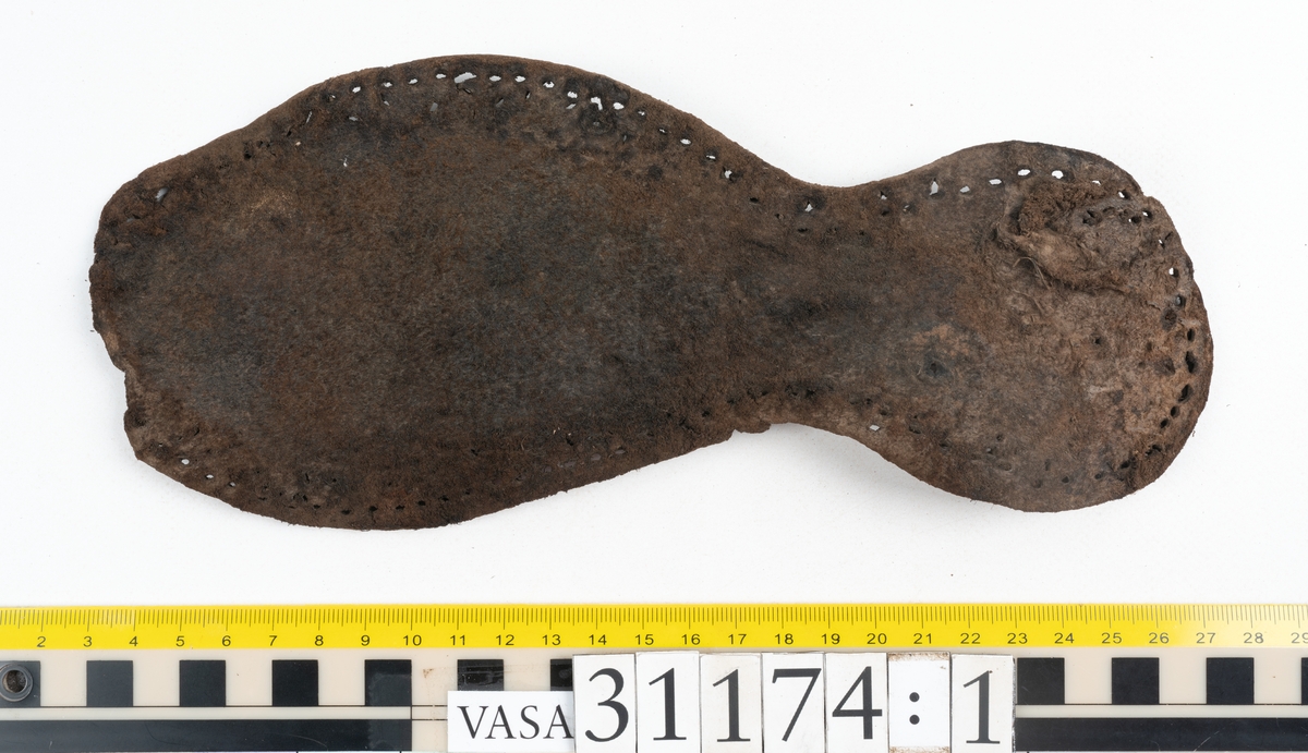 Delar av skobotten.
En sula med kvarsittande del av klacken. Sulan ligger vikt samt är delvis fragmentarisk. Längs med ytterkanterna löper hål efter stygn. Klacken består av fyra klacklappar. Två klacklappar är mycket fragmentariska. Klacken har kvarsittande tråd och träpligg.
En sula. Längs med ytterkanterna löper hål efter träpligg och stygn. Tåpartiet är något fragmentariskt. Lädret är mycket kraftigt.
En klacklapp. Klacklappen är något hästskoformad. På klacklappen syns stora hål efter träpligg.